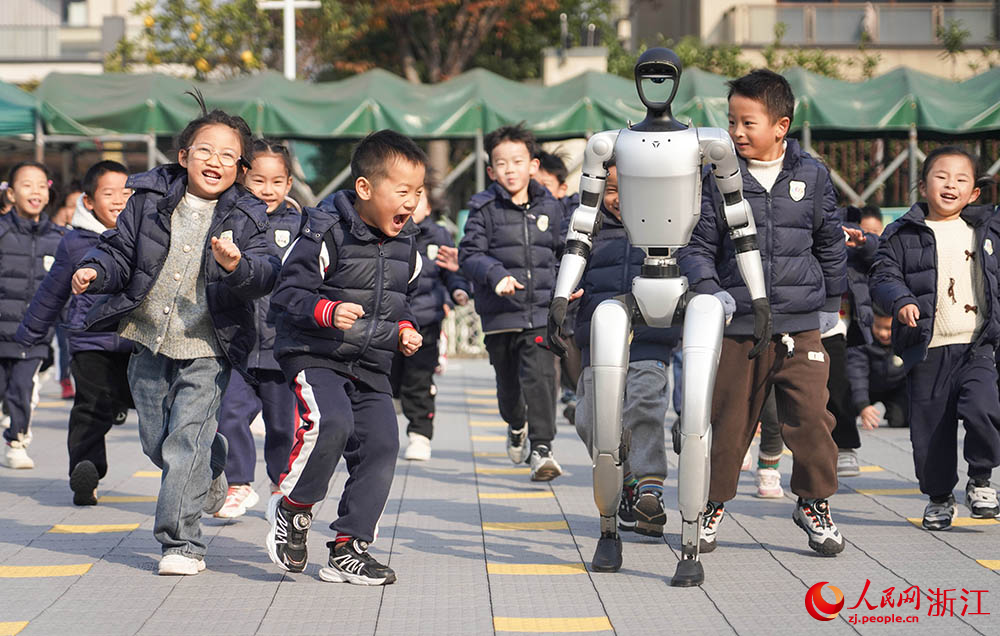 在寧波市江北區(qū)慈城懷之幼兒園，孩子們和人形機器人奔跑在校園里。人民網(wǎng) 章勇濤攝