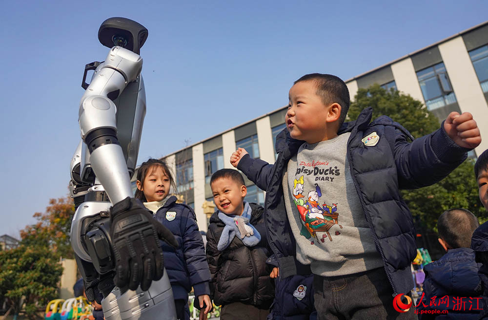 在寧波市江北區(qū)慈城懷之幼兒園，小朋友和人形機(jī)器人互動(dòng)。人民網(wǎng) 章勇濤攝